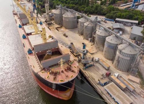 Процес завантаження зерна на судно в порту біля елеваторного комплексу