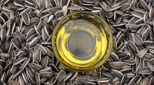 Ємність з соняшниковою олією посеред насіння соняшника